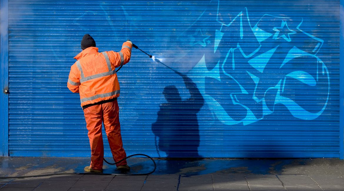 Washing graffiti off a security grill.